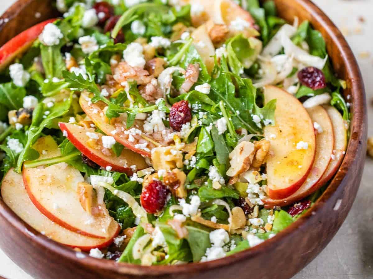 A bowl of apple walnut salad with arugula