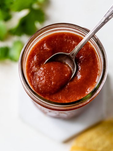 Spoonful of homemade red enchilada sauce in jar