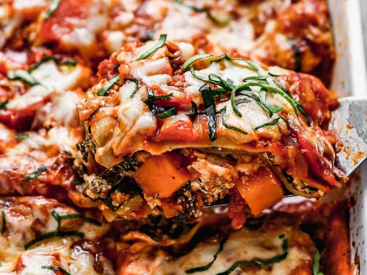 A piece of vegetable lasagna being cut from a dish