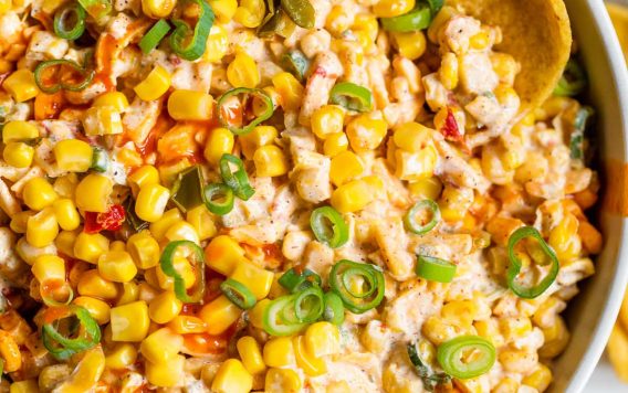 Fritos being dipped in a bowl of Mexican corn dip