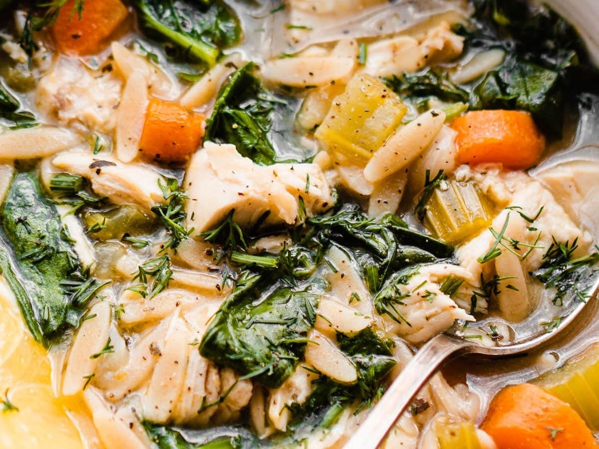 A bowl of healthy lemon chicken orzo soup with spinach