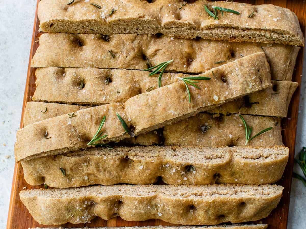 no knead focaccia sliced on a cutting board with sea salt and rosemary