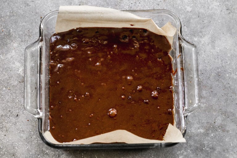 brownie batter in a parchment-lined 8x8 glass pan