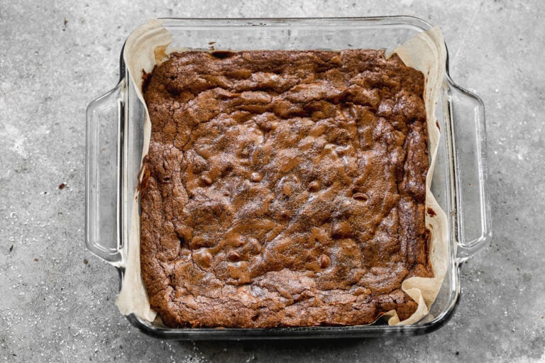 freshly baked one bowl brownies in an 8x8 glass pan lined with parchment paper