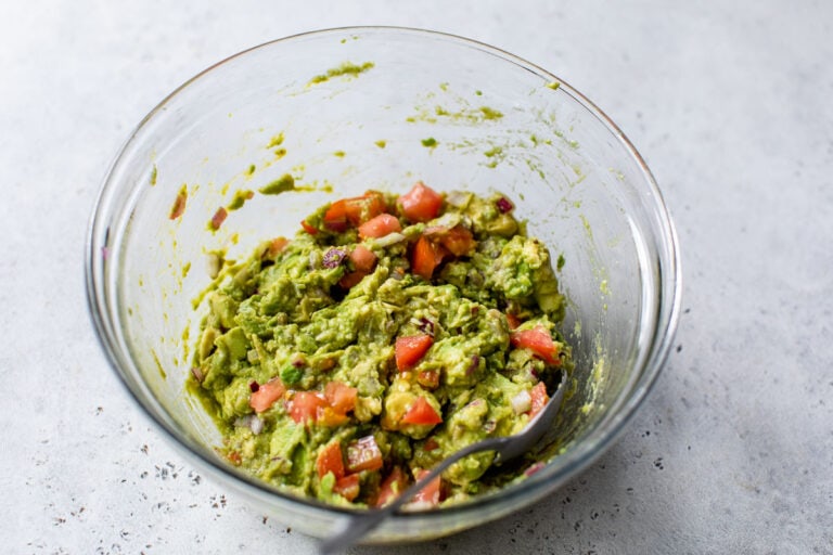 Mashed avocado and tomatoes in a bowl