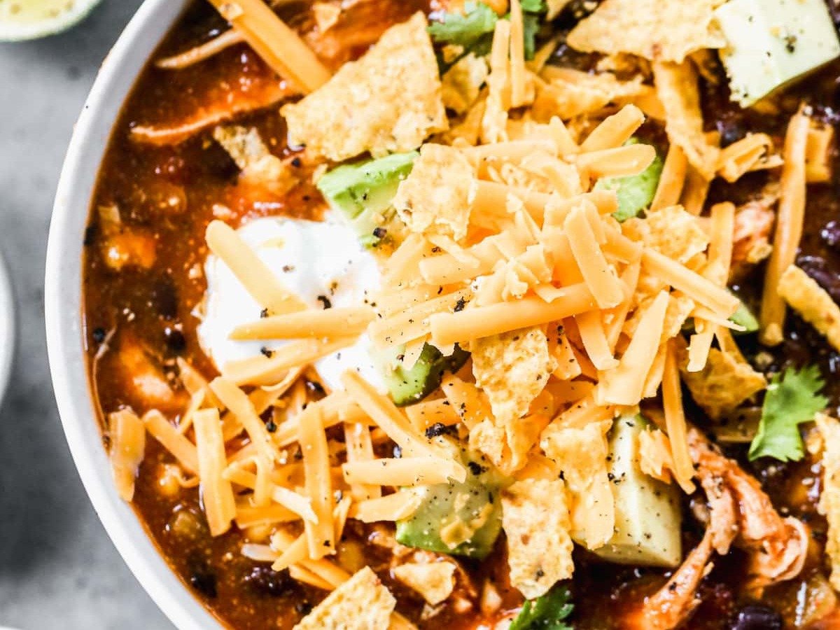 a bowl of crockpot chicken enchilada soup with cheese on top