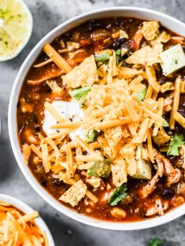 a bowl of crockpot chicken enchilada soup with cheese on top