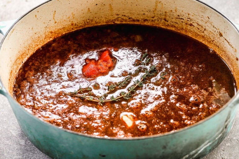 A flavorful sauce with vegetables and herbs in a Dutch oven