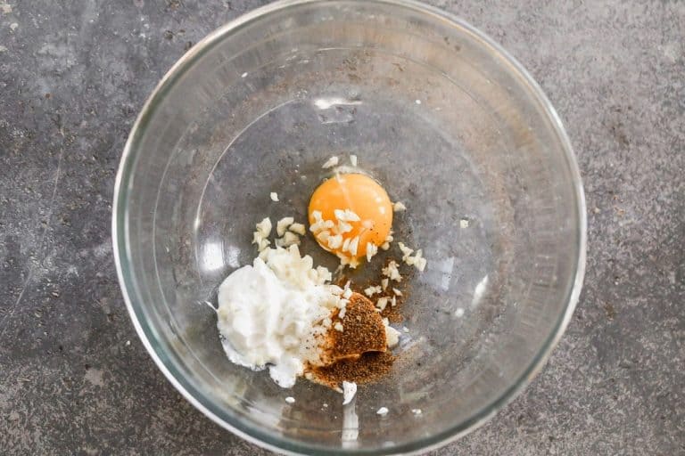 An egg yolk, yogurt, and spices in a bowl