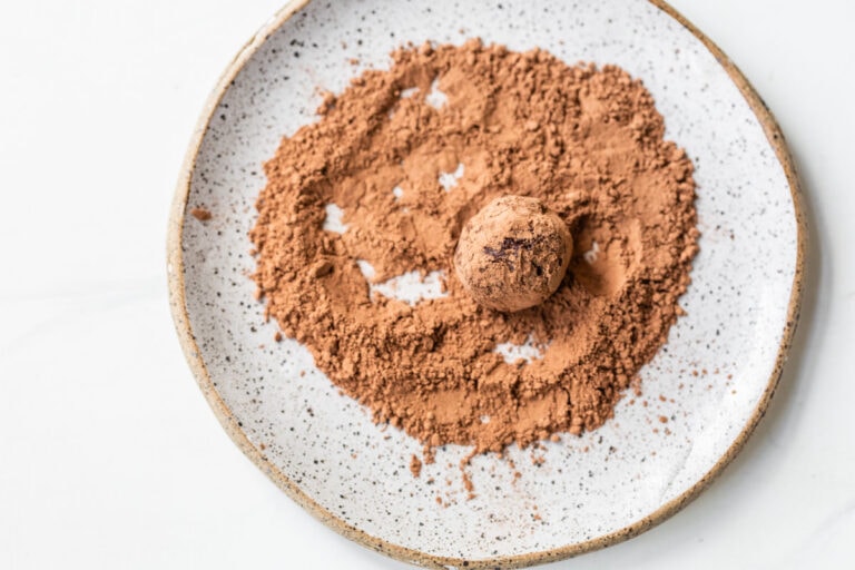 rolling a red wine ganache truffle in cocoa powder