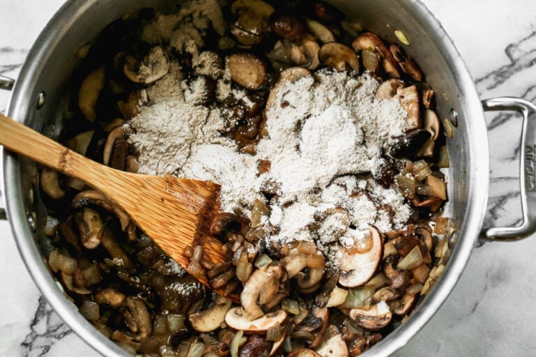 Flour being added to a pot of mushrooms and onions