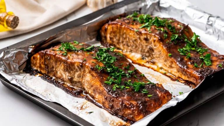 roasted balsamic glazed salmon garnished with parsley on a foil-lined sheet pan