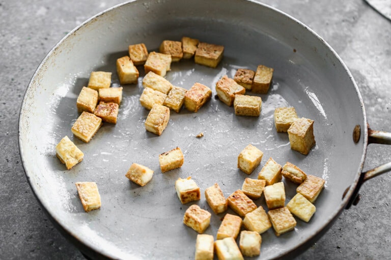 crispy tofu in a skillet cut into bite-sized pieces