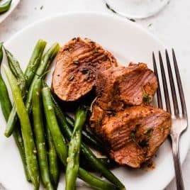 Slices of baked pork tenderloin and green beans on a plate
