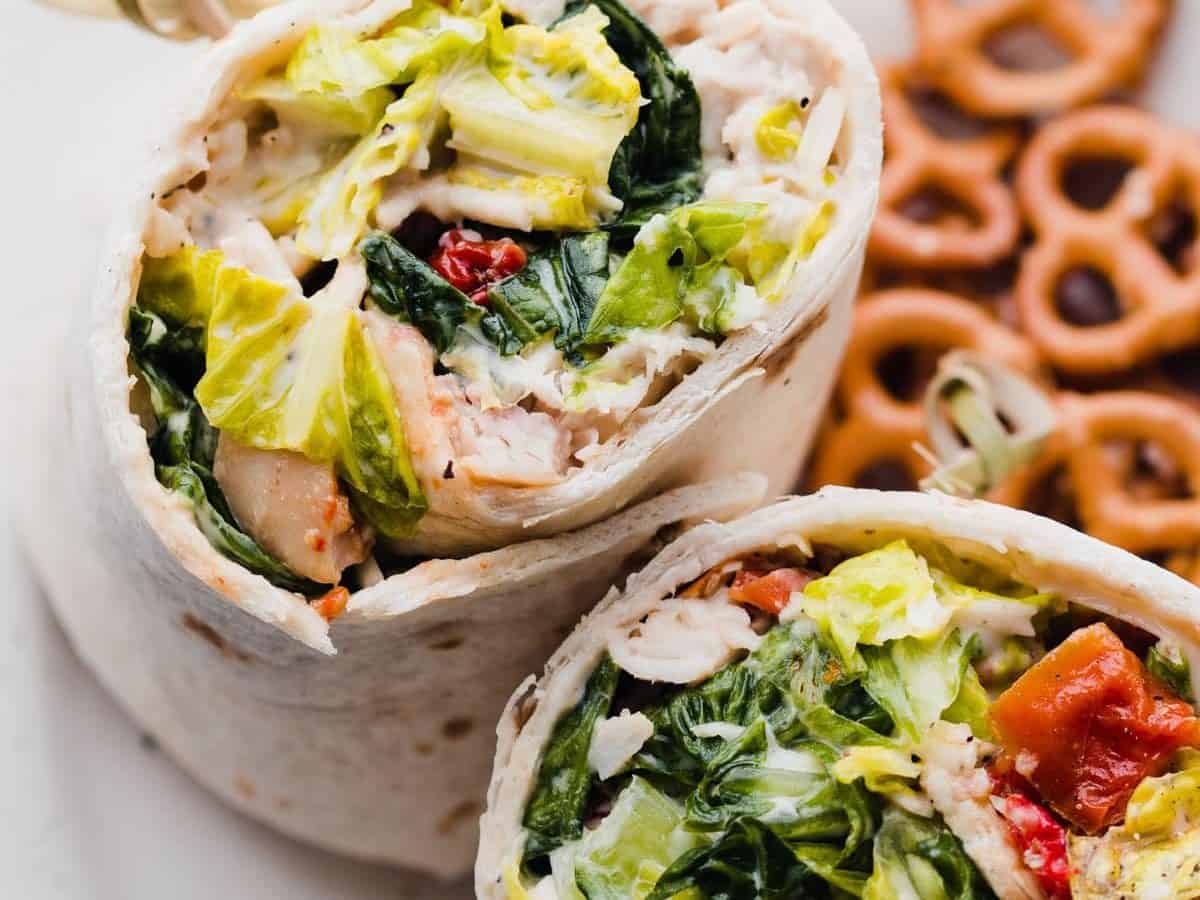 Chicken Caesar wraps on a plate with pretzels