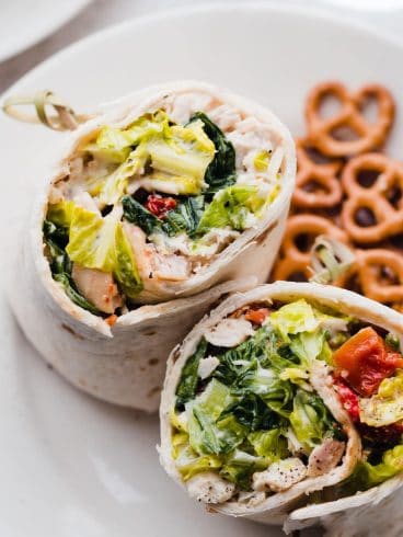 Chicken Caesar wraps on a plate with pretzels
