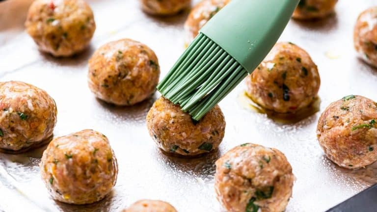 olive oil being brushed on meatballs