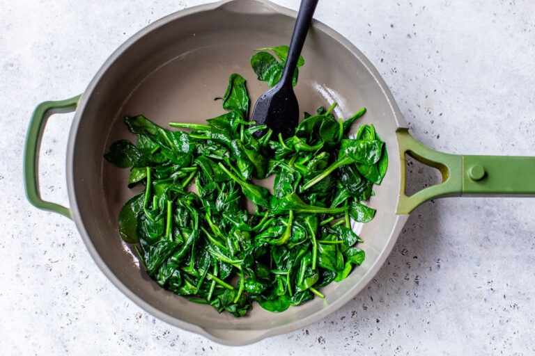 a skillet of fresh spinach being sauted