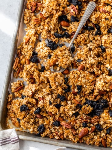 Overhead view of homemade granola on sheet pan with spoon