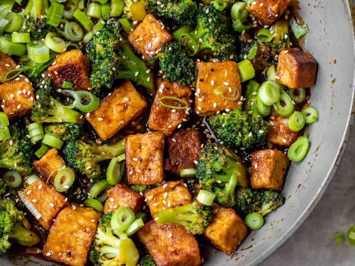 A wok with tofu, broccoli, and green onions