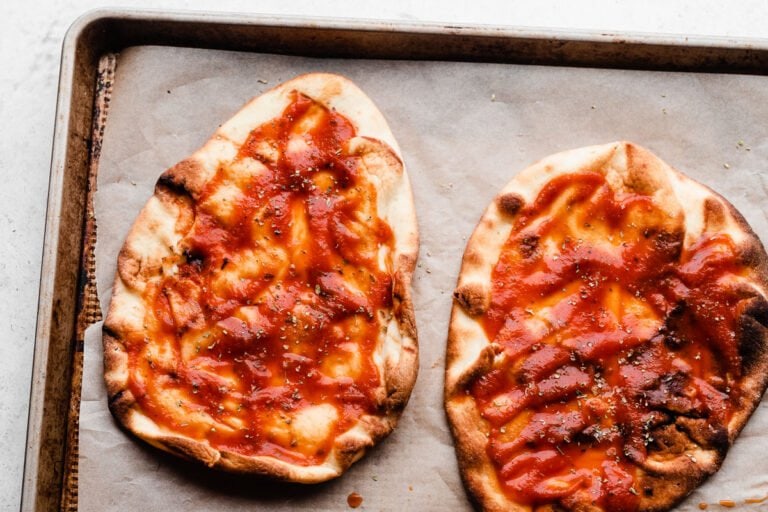 Sauce on two crusts on a baking sheet