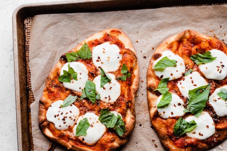 Two naan pizzas on a baking sheet