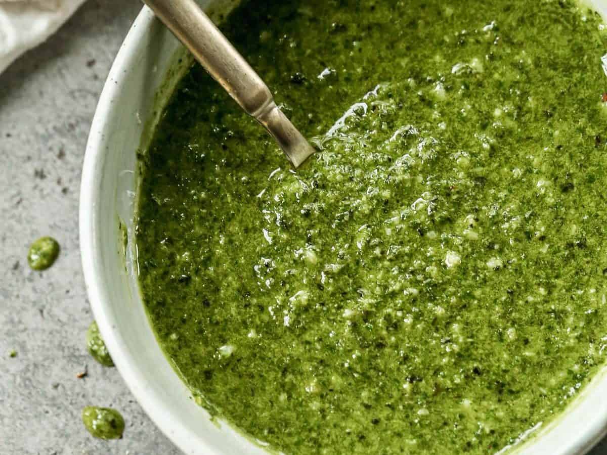 A bowl of basil pesto with a spoon