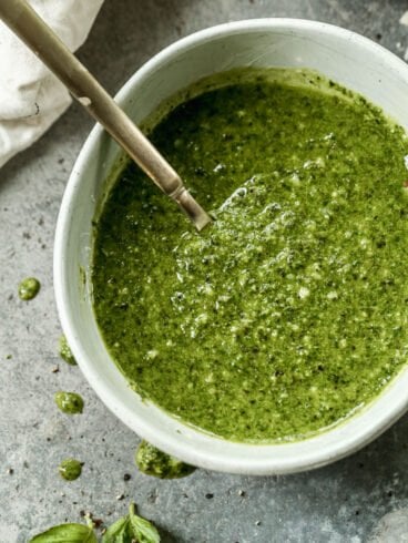 A bowl of basil pesto with a spoon