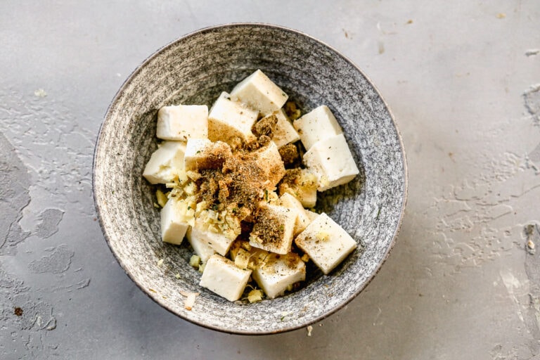 cubes of panner in a bowl with masala powder and spices