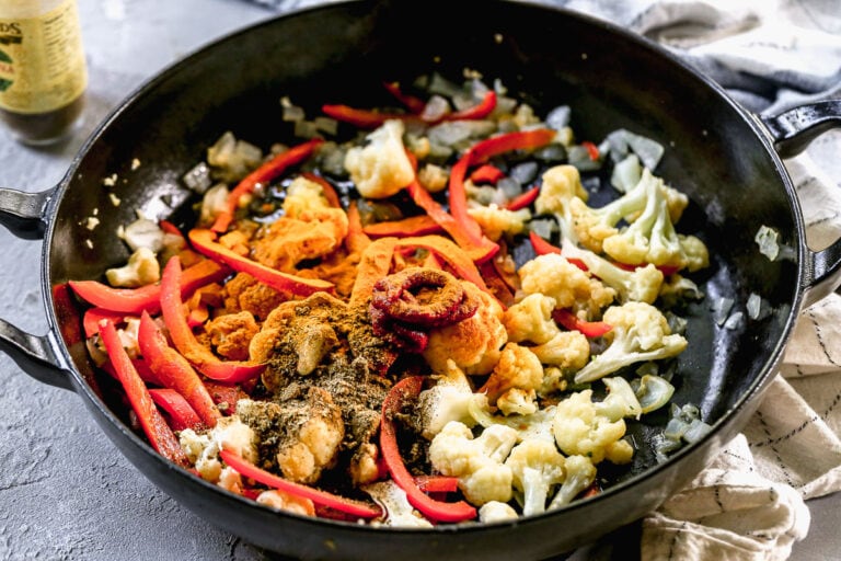 curry and garam masala powder spinkled over a skillet of sautéed vegetables