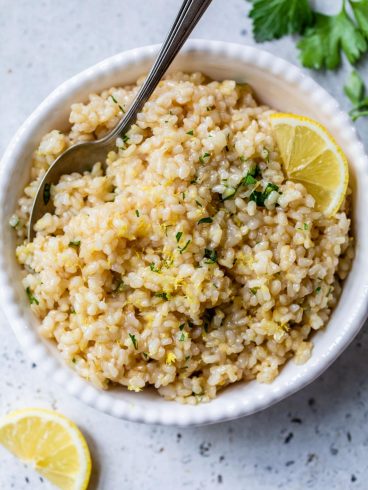 A spoon and bowl of the Best lemon rice recipe with parsley