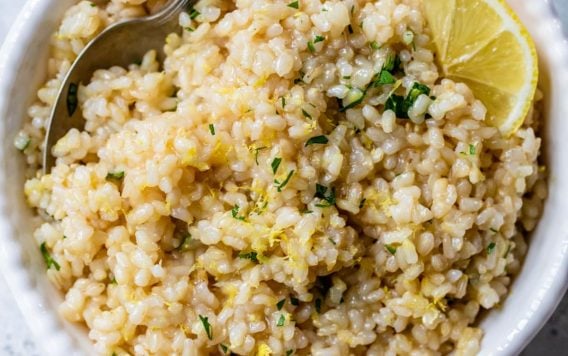 A spoon and bowl of the Best lemon rice recipe with parsley