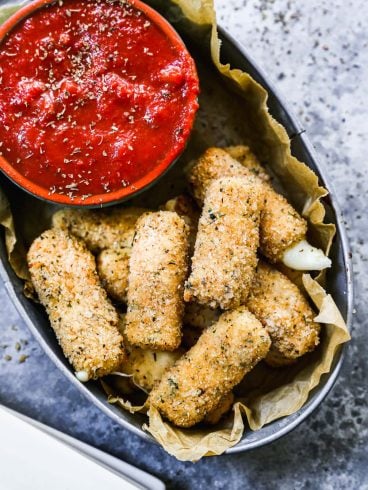 A basket of homemade air fryer Mozzarella sticks with marinara sauce