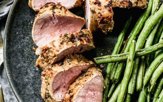 A plate with sliced air fryer pork tenderloin and green beans