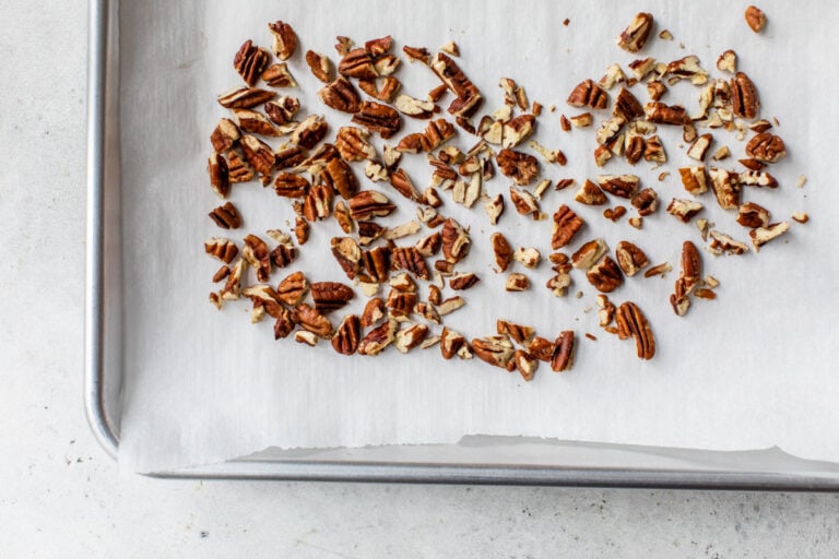 Chopped pecans on a parchment-lined baking sheet