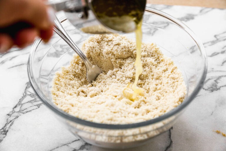 adding vegan butter to a bowl of almond flour