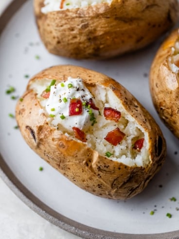 baked potatoes on plate with toppings