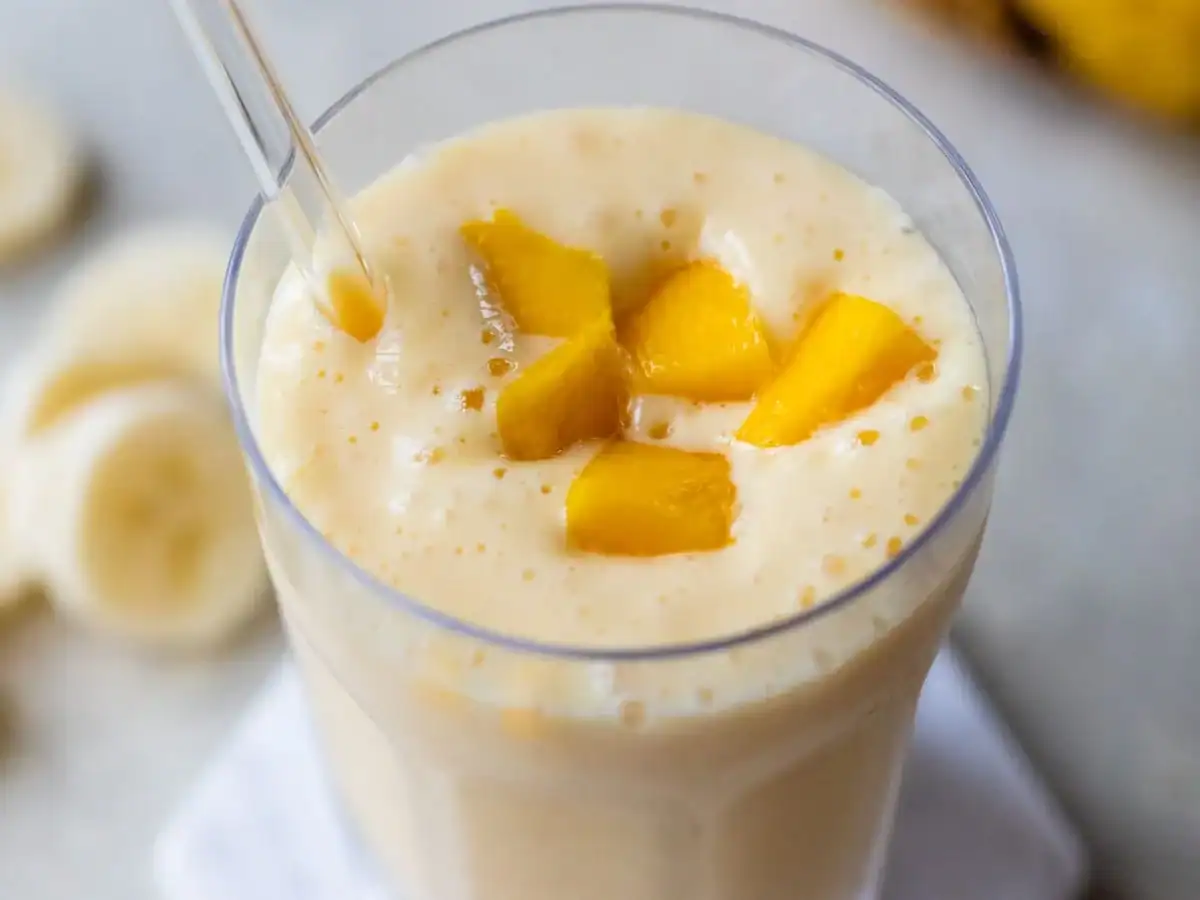 Mango smoothie in glass with straw