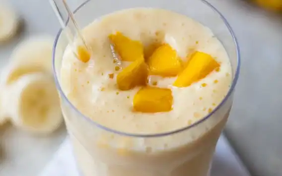 Mango smoothie in glass with straw