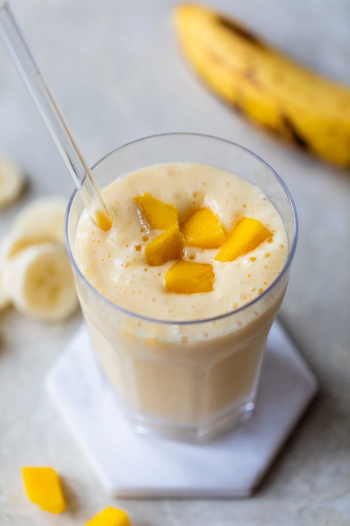 Mango smoothie in glass with straw