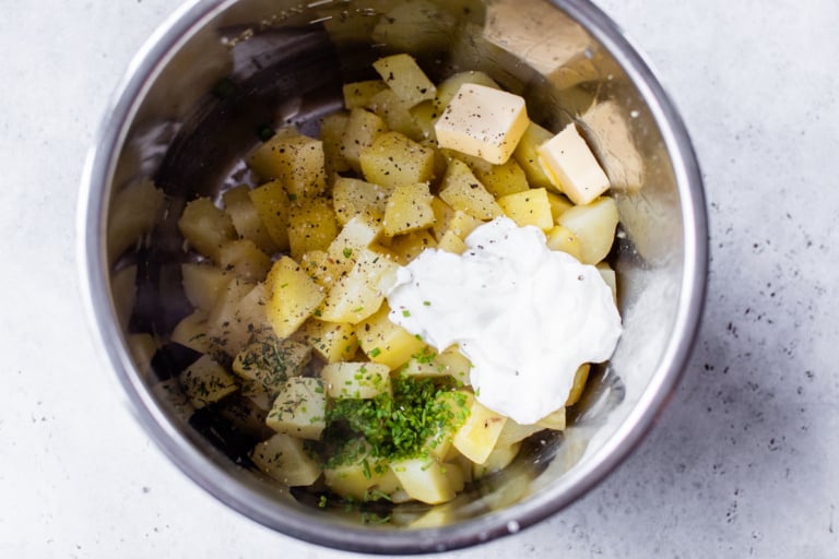 cooked potato pieces in an instant pot with herbs and greek yogurt