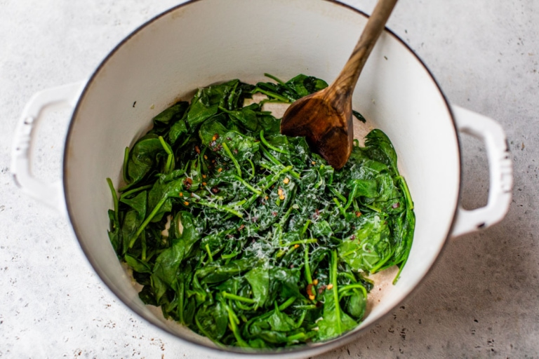 wilted spinach in a pot with seasoning