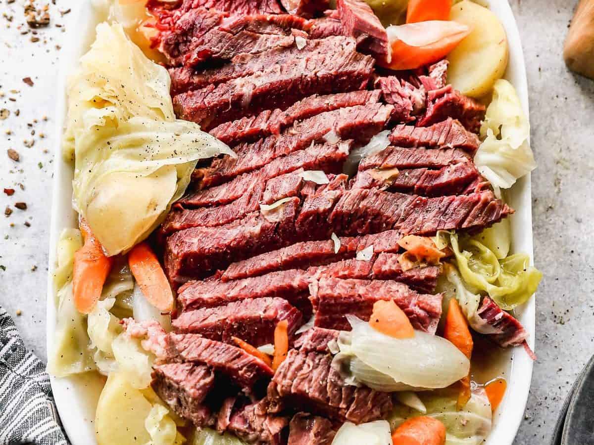 Sliced corned beef on a platter with carrots and cabbage