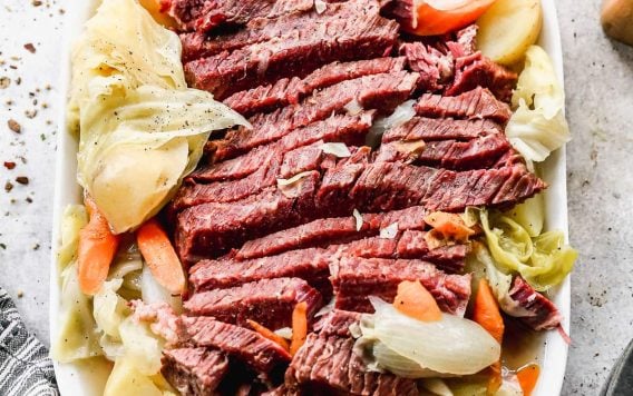 Sliced corned beef on a platter with carrots and cabbage