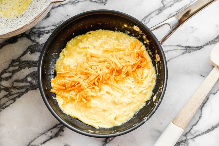 adding cheese to french omelette on a pan