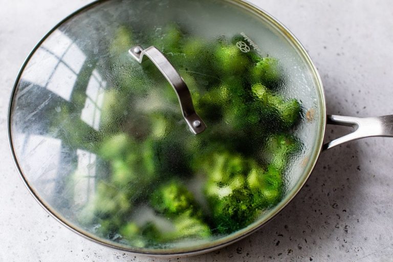 a pan of sauteed broccoli with a lid