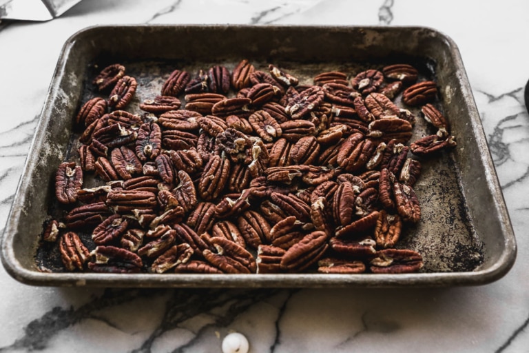 toasted pecans on a baking sheet to top bourbon pecan pie