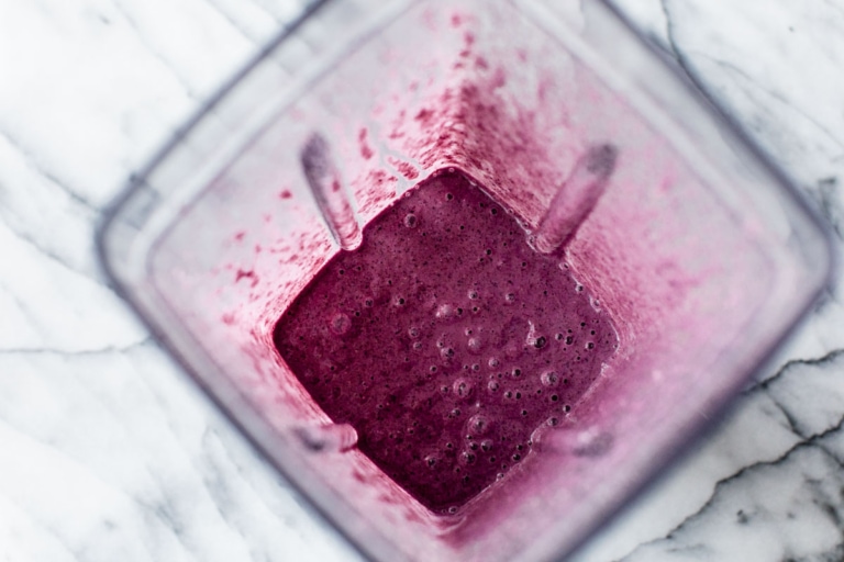 blended blueberry smoothie ingredients in a blender with milk and fruit