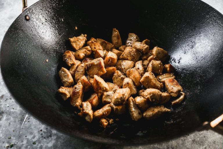 sauteeing chicken in a hot wok for chicken and broccoli stir fry