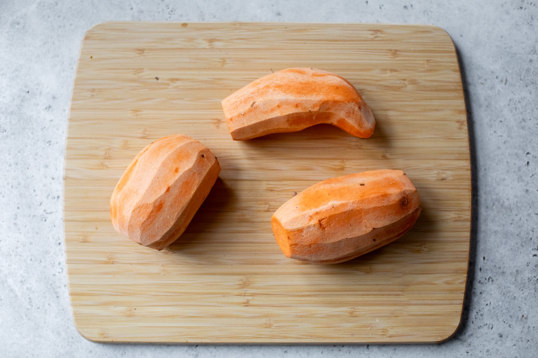 3 peeled sweet potatoes on cutting board